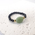 Macro dettagliata di un anello di perline con pietra naturale ovale verde su pietra bianca - Taglia unica / Nero-Verde