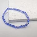 Detail of blue faceted crystal beads with AB coating on a minimalist white stone background - Blue