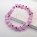 Macro view of pink evil eye beaded bracelet with resin charms on a white stone tile - Pink