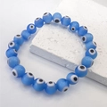 Close-up of blue glass Evil Eye beads on a beaded stretch bracelet with marble texture - Light Blue