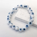 Detailed close-up of Evil Eye beaded stretch bracelet on a decorative stone slab - White Blue