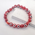 Close-up of red Evil Eye beads bracelet with elastic cord on white marble stone - Red