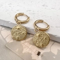 Detail of 18K gold star pendant earrings on white stone with embossed starfish pattern - Star Earrings / Gold
