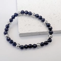 Detail eines Perlenarmbands mit dunkel facettiertem Glas und silbernen Trennperlen - Schwarz-Stahl