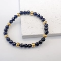 Detail von 6 mm dunkelblauen Facettenperlen und Goldperlen auf einem elastischen Armband - Schwarz-Gold