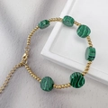 Dettaglio delle perle in oro 18K e pietre di malachite verde su bracciale con chiusura a moschettone - Malachite
