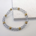 Macro shot of 6mm light blue faceted glass and gold steel beads on stretch bracelet - Gray-Gold