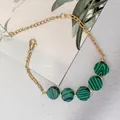 Dettaglio di un bracciale in acciaio dorato con cinque pietre di malachite verdi tonde - Malachite