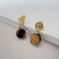 Gouden gehamerde hanger oorbellen met tijgeroogstenen op witte trapvormige achtergrond - Tijgeroog