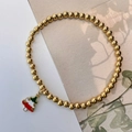 Macro detail of golden beaded elastic bracelet featuring a colorful Christmas tree charm - Christmas Tree