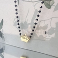 Vue détaillée du pendentif couronne dorée et du collier de perles noires - Couronne B