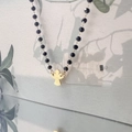 Close-up of black beaded necklace featuring a polished gold angel-shaped pendant - Angel