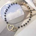 Dettaglio del bracciale bohémien con perline nere e doppi ciondoli a cuore dorati - Ciondolo a cuore