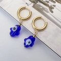 Detail of gold Hamsa hand earrings with blue Evil Eye glass pendants on a minimalist base - Blue