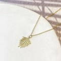 Vue détaillée du pendentif feuille de palmier dorée avec texture métallique et chaîne fine - Style Feuille (DN275)