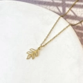 Detailed close-up of a delicate gold leaf pendant necklace on a white stone display - Willow Leaf Style (DN281) / Gold