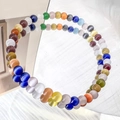 Macro detail of natural cat eye stone beads with light-reflecting shimmer on a bracelet - 4mm / Colorful