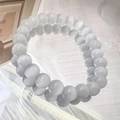 Detail of two white cat eye stone beaded bracelets with glossy finish on textured fabric - 8mm / White
