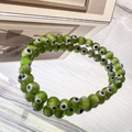 Macro detail of 6mm green glass evil eye beads on an elastic charm bracelet with reflections - 6MM Green