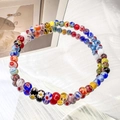Detailansicht bunter Millefiori-Glasperlen mit Gänseblümchen-Blumenmuster auf elastischem Band - 4mm Regenbogen