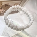 Detailansicht eines handgemachten Perlenarmbands mit Marmormuster auf Glashintergrund - 6mm Weiß