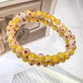 Macro detail of handmade yellow glass beads with daisy patterns on an elastic bracelet - 6mm Yellow
