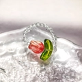 Detail von Perlenring mit roter Tulpe und klaren Glasperlen auf gewellter Glasoberfläche - Rot