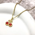 Minimalist red cherry pendant necklace with gold chain on white ceramic display plate - Red Zirconia Style