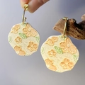 Detalle de pendientes florales crema hechos a mano con pétalos de flores en relieve naranja - Verde