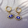 Macro view of gold hoop earrings featuring blue enamel evil eye charms on purple waves - Style A Eye