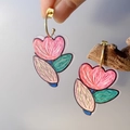 Close-up of floral acrylic earrings with hand-painted pink and green stripe patterns - Tulip