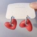 Dettaglio ravvicinato di orecchini a cerchio in acciaio con ciondoli a cuore rosso 3D - Acciaio-Rosso