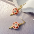 Macro detail of ceramic plum blossom earrings with gold-plated stainless steel accents - Pink