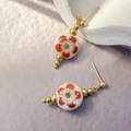 Detail of Chinese style ceramic earrings with red plum blossom pattern and gold finish - White