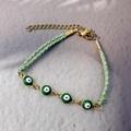 Close-up of green evil eye beads on 18K gold-plated chain and braided rope bracelet - Black