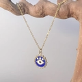 Detail der goldenen Evil Eye Halskette mit blauem Emaille an einem Holzast hängend - Runde Medaille (勋章)
