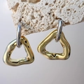 Dettaglio di orecchini geometrici a triangolo cavo su supporto in pietra naturale - Argento con Oro