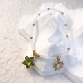Dettaglio del bracciale con perline bianche, ciondolo sole dorato e stella verde su pietra - Bianco - Stella Verde