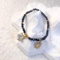 Detailed shot of black glass beaded bracelet with gold star and sun charms on white decor - Black - Clear Star