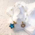 Detail of matte white bead bracelet with blue star gem and golden sun pendant charms - White - Blue Star