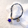 Detail of beaded bracelet with black crystals, golden sun and blue star charms on white stone - Black - Royal Blue Star