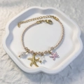 Détail du bracelet en corde tressée avec perles, pendentifs étoile et fermoir mousqueton - Rose