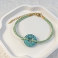Macro shot of green stone donut bead on a handmade mint green braided bracelet - Turquoise