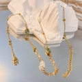 Dettaglio collana vintage dorata con gemme verde acqua e perle su supporto in pietra - Ovale-Blu
