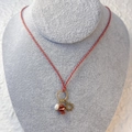 Detail of woven rope necklace featuring a sun pendant, natural stones, and a white pearl - Sun (Red Gold Cord/Red Natural Stone)