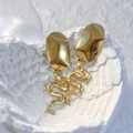 Dettaglio macro di orecchini a serpente placcati oro 18K con trama a scaglie su bianco - Ellisse / Oro