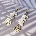Close-up of tropical fish earrings with shell beads and golden abstract charms - White