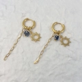 Dettaglio di orecchini a sole dorati con perline a fiori blu e nappe a catena - Sole