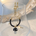 Detailaufnahme des bunten Pilzanhängers mit schwarzen Perlen an goldener Kette - Schwarz