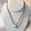 Macro detail of bohemian braided necklace with a blue spotted mushroom pendant - Blue